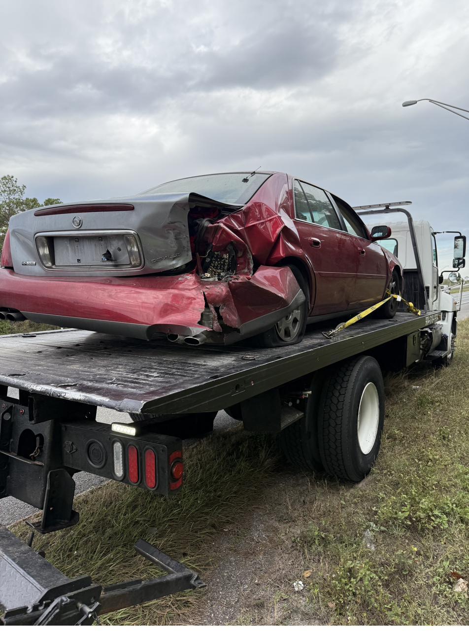 Wrecked Cadillac DeVille secured on a flatbed after an accident