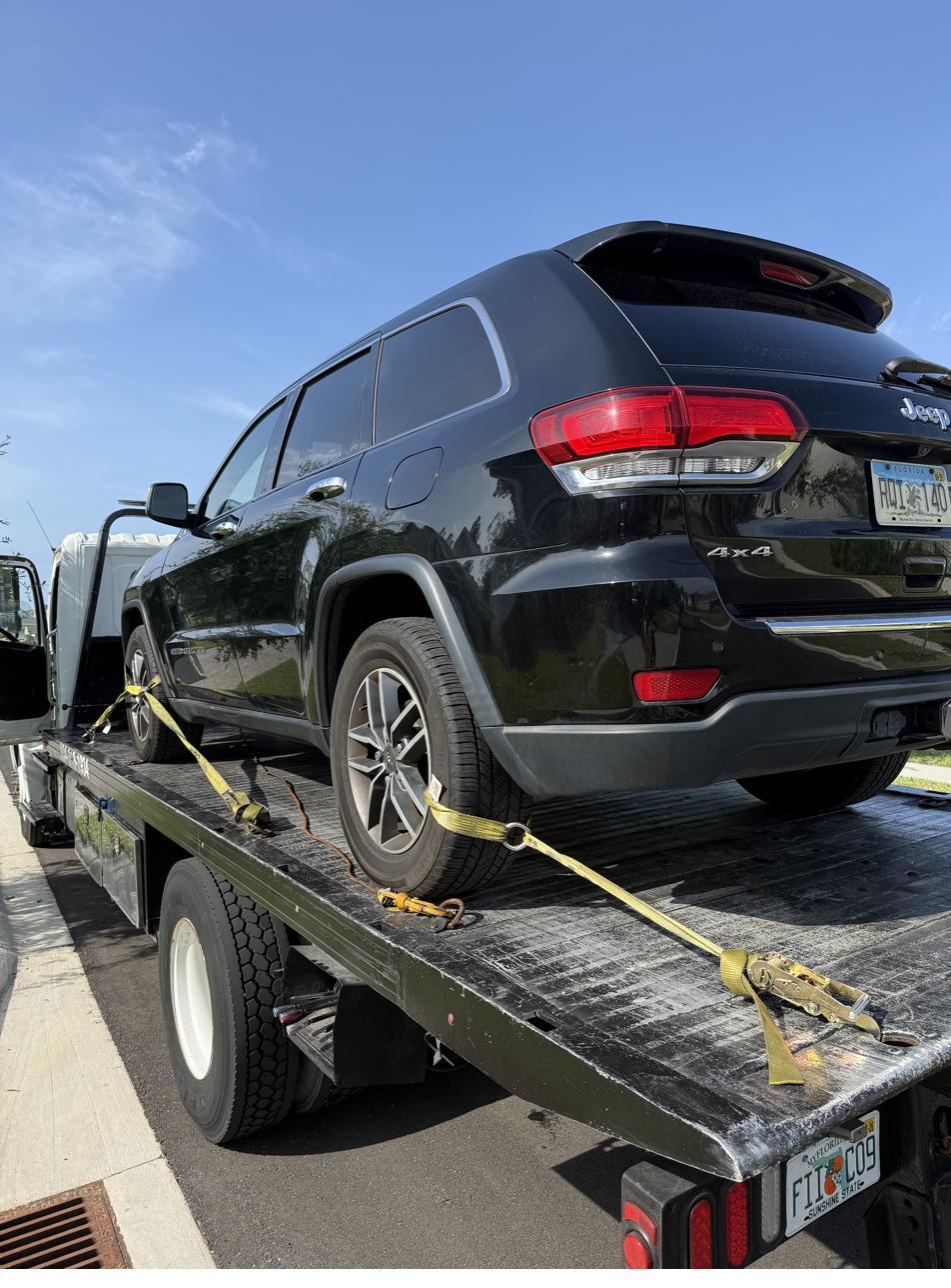Black Jeep Grand Cherokee secured on a flatbed for transport