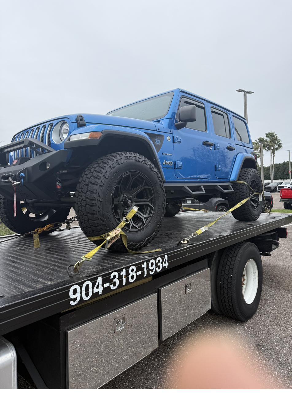 Blue Jeep Wrangler loaded on a Hammond flatbed tow truck